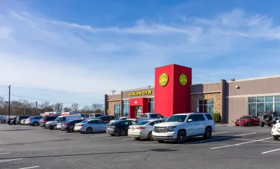 Red and yellow Gold's Gym building with parking lot in front in Harrisburg, North Carolina.
