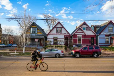 Cyclist rides past row of colorful historic homes in Denver, Colorado.