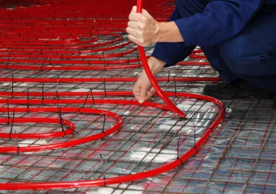 A person lays down red geothermal pipes.