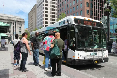 White RIPTA transit bus in Providence, Rhode Island with crowd of passengers boarding at bus stop.