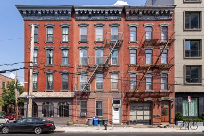 Red NYC brick apartment buildings with closed, unlabeled comemrcial space on ground floor.