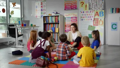 Children sitting around teacher in day care or kindergarten classroom.