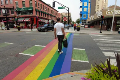 Man crossing rainbow-painted crosswalk in Hoboken, New Jersey.