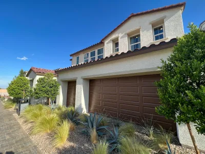 Neo-Spanish style new house with brown garage door and xeriscaped small yard.