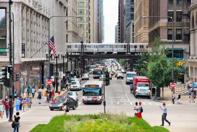 People in Chicago cross the street. There are two CTA buses in the background.