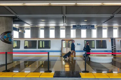Two people walking in front of stopped BART train at station in San Francisco Bay Area.