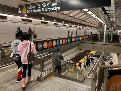 Two young women prepare to step onto the escalator to the lower subway platform of New York City's Second Avenue Line.