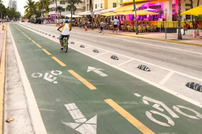 Man riding bike in green painted and protected bike lane in Miami, Florida.