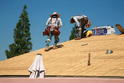 Workers on a wood roof building a home.