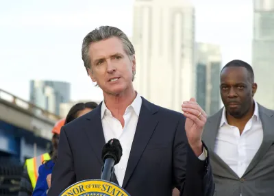 Gavin Newsom speaks behind a podium and gestures with one hand.