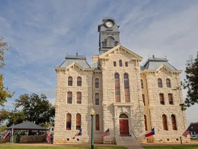 Old Hood County courthouse made of white stones with clock tower in Texas.