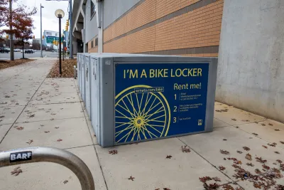 WMATA bike lockers on sidewalk at Tysons Corner, Virginia with large stickers on sides saying "I'm a Bike Locker - Rent Me" with information.