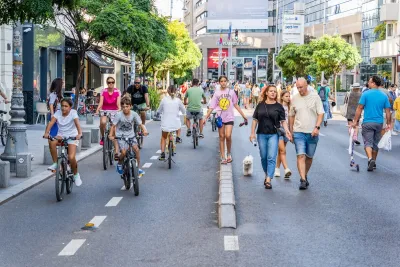 Busy street closed to vehicles in center of Bucharest, Romania full of pedestrians and people on bikes and scooters.