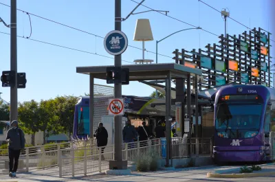 Purple Phoenix light rail car at station with decorative glass panels.