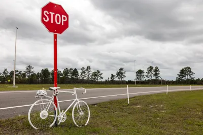 White memorial ghost bike tied to a stop sign on rural road.