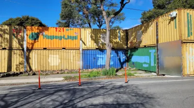Colored shopping containers stacked two-high as a wall closing off People's Park in Berkeley, California.