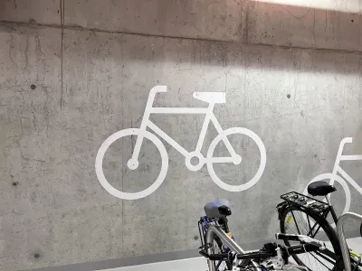 Bike parking logo on concrete wall in garage with parked bike visible in bottom corner.