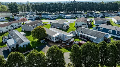 Aerial of mobile home park with double-wide trailers being isntalled on green lawn.