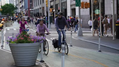 Two people wearing helmets riding bikesi n green protected New York City bike lane.