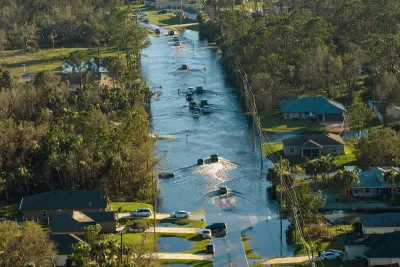 urricane flooded street with moving cars and surrounded with water houses in Florida residential area.