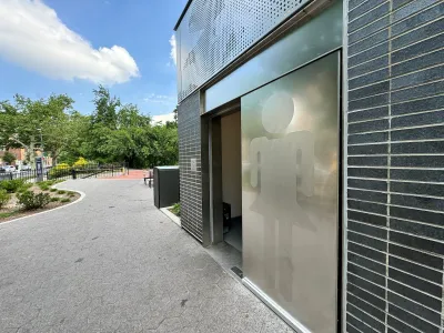 Modern public restroom with silver door in park in New York City.