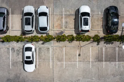 Bird's eye view of white cars in parking lot.