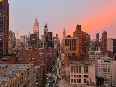 Midtown Manhattan skyline with Chrysler Tower in background against colorful sunset.