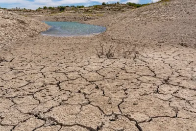 Dried-up cracked soil next to a receding puddle.
