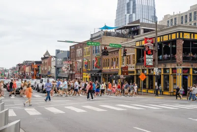 Crowd of people in crosswalk on busy street in downtown Nashville, Tennessee.