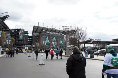 People walking toward Lincoln Field football stadium in Philadelphia in Eagles gear.