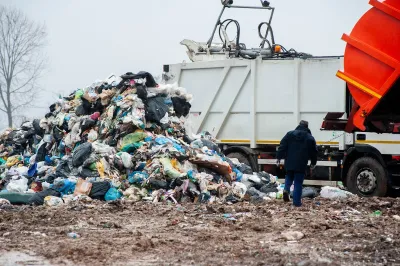 A worker supervises the dumping of waste at a landfill.