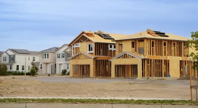 Wood-frame houses under construction next to completed houses.