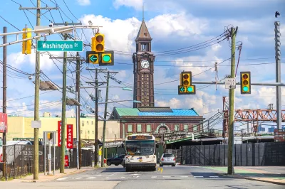 Street in Hoboken, New Jersey with old brick building with clock tower in background and public bus driving toward camera.