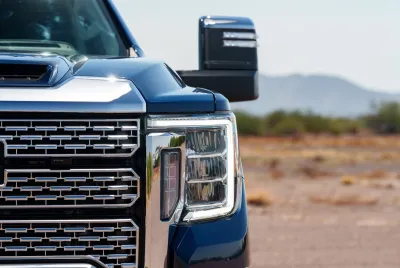 Close-up on silver grill of large blue pick-up truck.