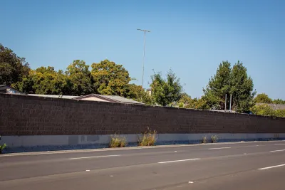 Concrete sound wall next to empty freeway.