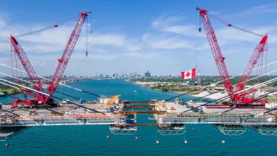 Red cranes over Gordie Howe Bridge spanning Detroit River.