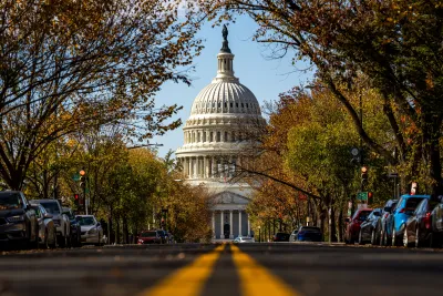A road, lined with cars, leading to the United States Capital Building.