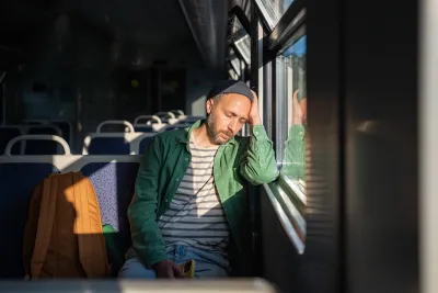 Tired man leaning on window sleeping on bus or tram.