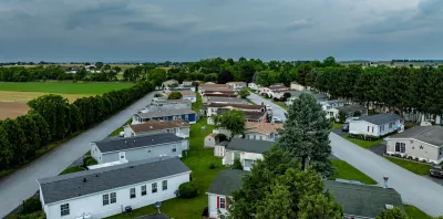 Home Park with many houses and trees. The houses are white and the trees are green. The sky is cloudy and the houses are spread out.