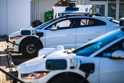 White Waymo cars parked at charging station.