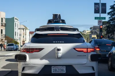 White Waymo self-driving car in San Francisco, CA at red traffic light.