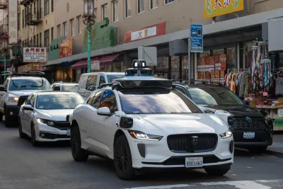 White Waymo self-driving car with camera on top in San Francisco, CA.