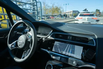Interior of self-driving car with white car in front of it on the road.