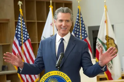 Gavin Newsom gesturing with both hands out behind a podium.