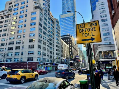 Yellow "last turn before toll" sign on post on busy street in New York City.
