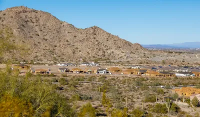 Aerial of houses under construction in Buckeye, Arizona against desert mountains.