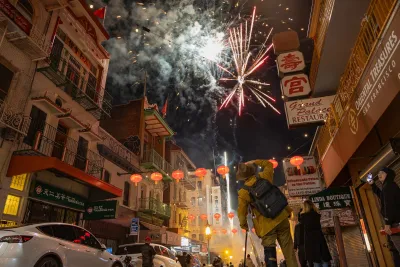 Fireworks going off above San Francisco urban street.