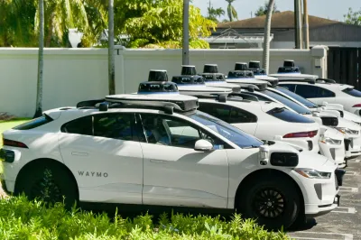 White Waymo self-driving cars parked in a row in Miami, Florida.