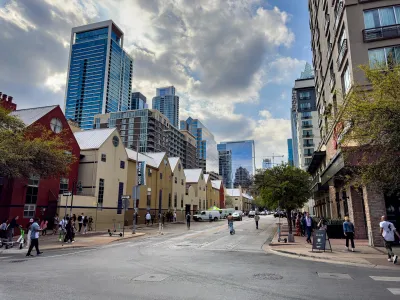 Street with two-story apartment buildings in Austin, Texas with downtown skyline visible in background.