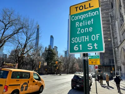 Close-up of green congestion relief zone sign in New York City with yellow cab van on street in background.